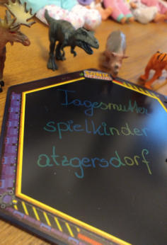 Tafel mit der Aufschrift Tagesmutter Spielkinder Atzgersdorf, daneben Spielzeugtiere